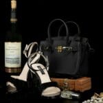 Czarna torebka i szpilki z biżuterią i winem na eleganckim tle