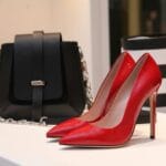 Czerwone szpilki i czarna torebka na tle luksusowego butiku