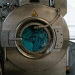 Przemysłowa pralka wypełniona niebieskimi tkaninami w pralni