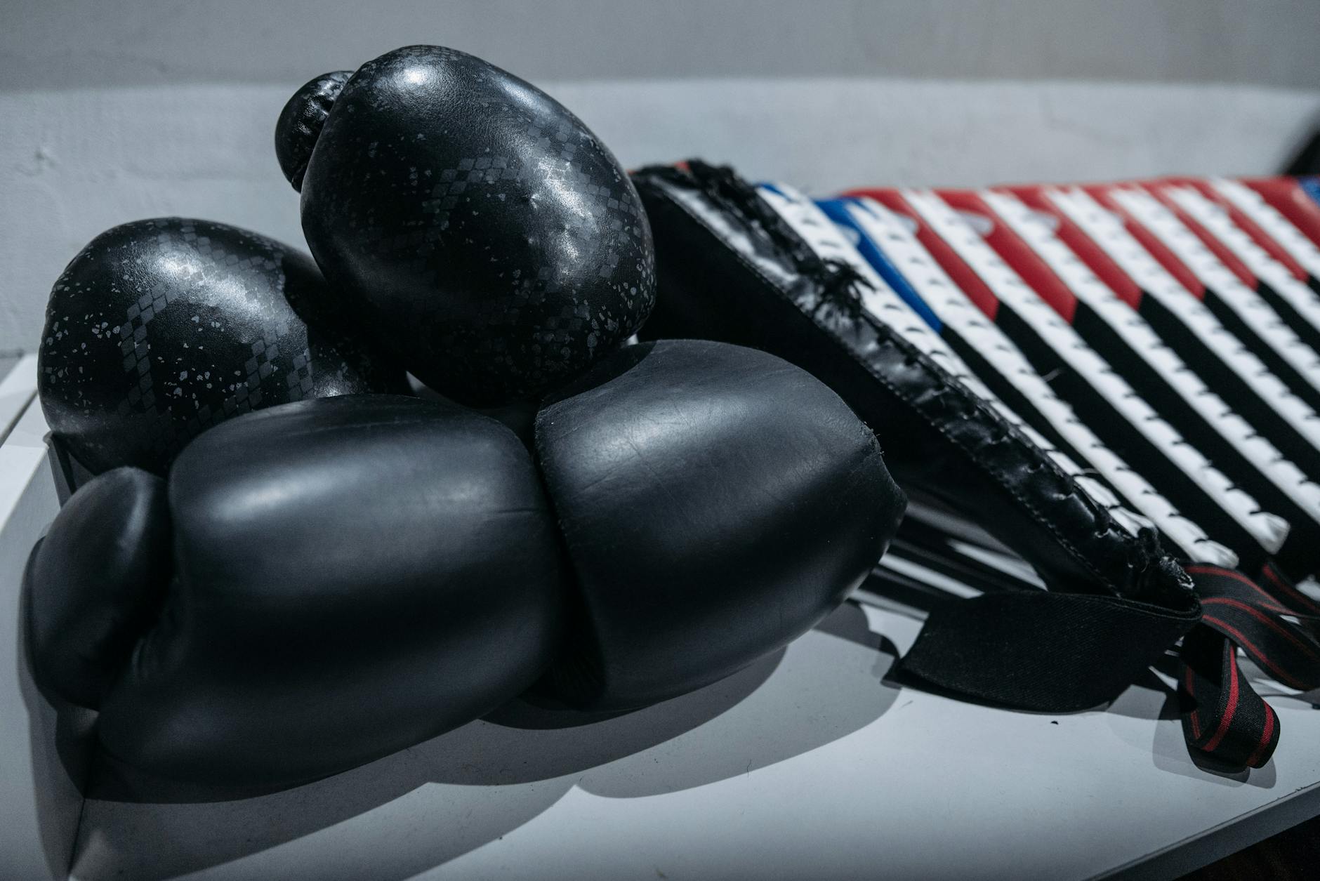 Czarne rękawice bokserskie leżące na stole obok sprzętu do sztuk walki