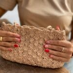 Kobieta trzyma ręcznie robioną szydełkowaną torebkę z misternym splotem