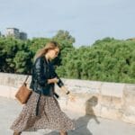 Kobieta w kwiecistej sukience i skórzanej kurtce z torebką na ramię