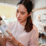 Młoda kobieta w sklepie uważnie czyta etykietę produktu