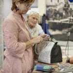 Rękodzielniczka sprawdza detale skórzanej torebki przy kliencie