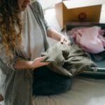 Kobieta na łóżku pakuje torbę podróżną na weekendowy wyjazd