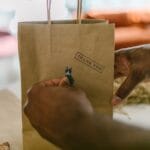 Dłonie trzymają papierową torebkę z napisem thank you jako opakowanie prezentu