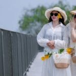 Dwie kobiety w letnich sukienkach i kapeluszach na słonecznym spacerze