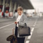 Kobieta z walizką i torebką idzie do terminala lotniska w podróży biznesowej