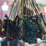 Kolorowe, błyszczące torebki handmade z cekinami wiszące obok siebie