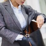 Zbliżenie: kobieta w kraciastej marynarce szuka w skórzanej torebce