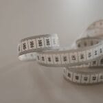 Zwinięta biała miarka krawiecka z czarnymi cyframi na tle stołu